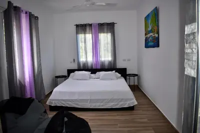 a bedroom with a white bed with purple curtains at Villa Laëti in Las Terrenas
