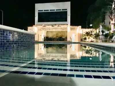 a swimming pool in front of a house at night at Elegante Aqua Marine Apartamento Juan Dolio in Juan Dolio