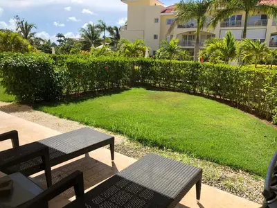 a patio with two benches and a grassy yard at Beautiful One Bedroom unit with pool and Beach club in a Golf Project in Punta Cana