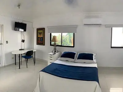a white bedroom with a bed and a table at Cozy Private Room in El Malecn, Santo Domingo in Santo Domingo