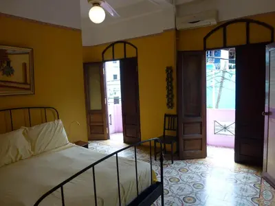 a bedroom with a bed with yellow walls and doors at Residencial La Fonte in Santo Domingo