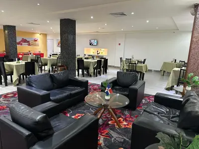 a restaurant with black leather furniture and tables and chairs at Ramada by Wyndham Princess Santo Domingo in Santo Domingo