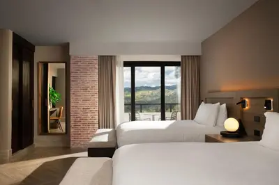 a hotel room with two beds and a large window at Camp David Ranch in Santiago de los Caballeros