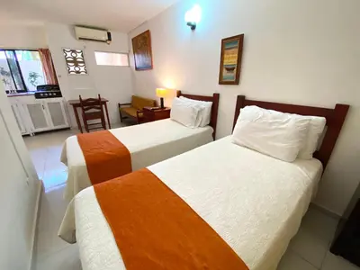 a hotel room with two beds and a chair at Hotel Alegria in Cabarete