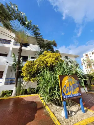 a sign in front of a building with a palm tree at Calypso Beach Hotel in Boca Chica