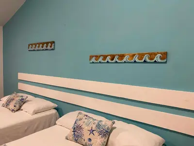 two beds in a room with blue walls at Calypso Beach Hotel in Boca Chica