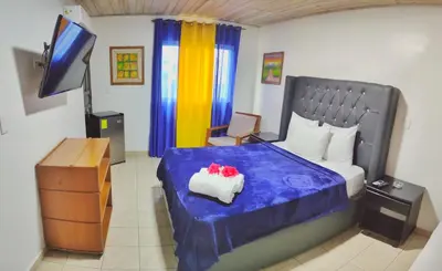 a bedroom with a bed with a blue blanket and a television at Acuarium Suite Resort in Santo Domingo