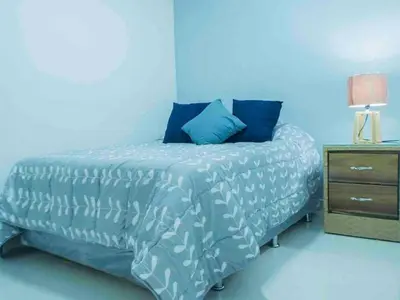 a blue bedroom with a bed and a night stand at Malecon Cozy Private Room 6 in Santo Domingo