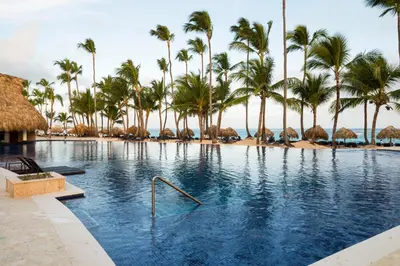 a swimming pool with palm trees and a beach at Royalton Punta Cana, An Autograph Collection All-Inclusive Resort & Casino in Punta Cana