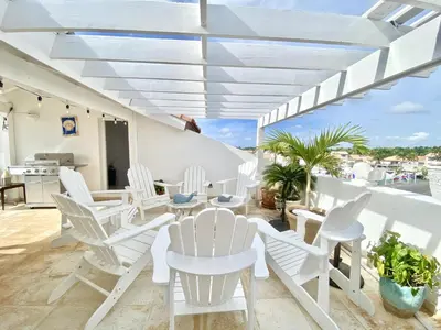 a patio with white chairs and tables on a balcony at Unique Luxury Pent House At Marina Casa De Campo in La Romana