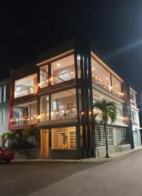 a lit up building with a palm tree in front of it at Apartahotel MACADANA in Nagua