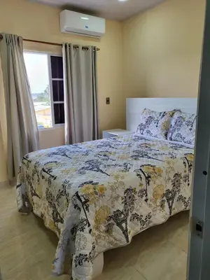 a bedroom with a bed with a floral bedspread and a window at Apartahotel MACADANA in Nagua