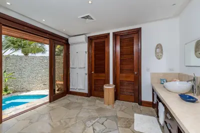 a bathroom with a tub and a sink and a pool at Unique Villa with Ocean and River Views - Staff & Golf Carts in La Romana