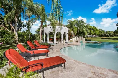 a group of red chairs sitting next to a swimming pool at Moroccan-Style Paradise with Pool & Maid at Casa de Campo in La Romana