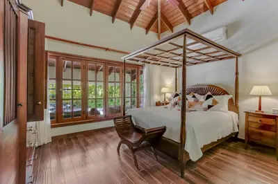 a bedroom with a canopy bed and a chair at Beautiful Villa with Pool, Gym & Maid in Punta Cana