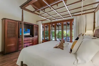 a bedroom with a large white bed and a television at Beautiful Villa with Pool, Gym & Maid in Punta Cana