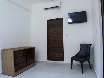 a room with a chair and a dresser and a television at Malecon Premium Rooms in Santo Domingo
