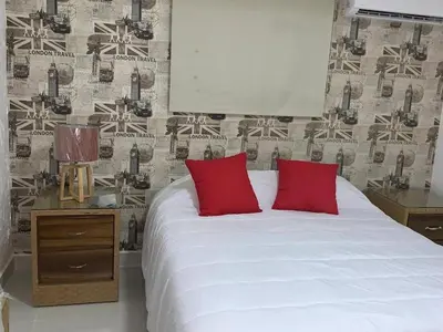 a bedroom with a white bed with red pillows at Malecon Cozy - Premium Plus 19 in Santo Domingo