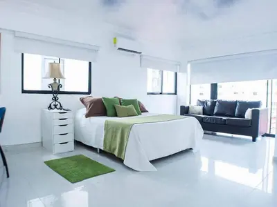 a white bedroom with a bed and a couch at Malecon Cozy - Premium Plus 13 in Santo Domingo