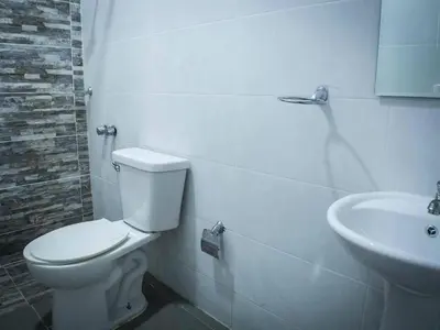 a white bathroom with a toilet and a sink at Malecon Cozy - Premium Plus 11 in Santo Domingo