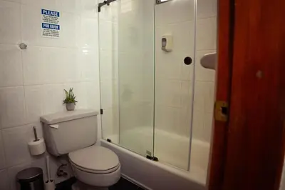 a bathroom with a toilet and a glass shower at Residenciales H1 & H2 - Breakfast & Room Service - Airport close in Santiago de los Caballeros