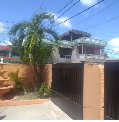 a house with a gate and a palm tree at Caribean House in Boca Chica