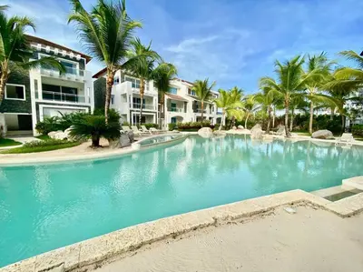 a swimming pool in a resort with palm trees at Beautiful Apt Dominicus Bayahibe, Walk To Beach! in La Laguna