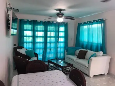 a living room with blue curtains and a couch at La Gaviota A3 in Juan Dolio