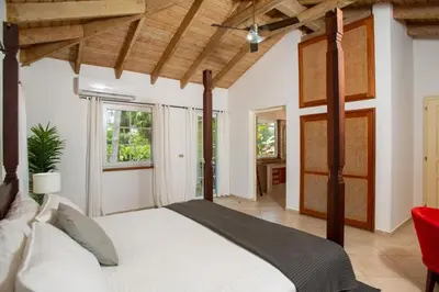 a bedroom with a large bed and a red chair at Exclusive Villa at Hideaway Beach in Cabarete