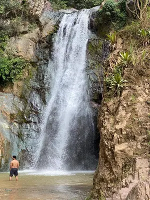 a man standing in the water in front of a waterfall at Haus unter Palmen in Jarabacoa