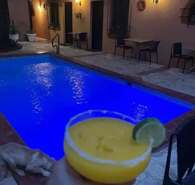 a drink in a persons hand next to a swimming pool at Mansion Colonial Boutique Hotel Pool Jacuzzi Bar Restaurant by BTC Group Crypto in Santo Domingo