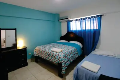 a blue bedroom with a bed and a mirror at Hostal Magisterial Santo Domingo in Santo Domingo