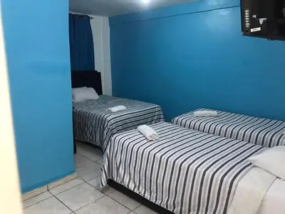 two beds in a room with a blue wall at Hostal Magisterial Santo Domingo in Santo Domingo