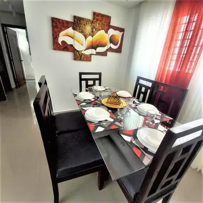 a dining room table with chairs and a glass table with plates at Your Space piscina, parque infantil, 3 habitaciones , Res Breezes Santiago in Santiago de los Caballeros