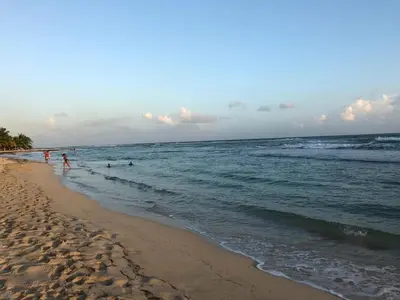 a beach with people swimming in the ocean at La Gaviota B1 in Juan Dolio