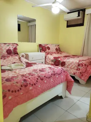 a bedroom with two beds and a mirror at Hotel Victoriano in San Felipe de Puerto Plata