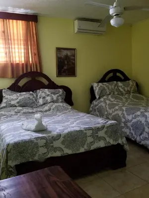 a bedroom with two beds and a table at Hotel Victoriano in San Felipe de Puerto Plata