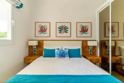 a bedroom with a large bed with blue pillows at Apartamento Acceso Directo a la piscina A-108, A-120, A-117 y B-137 in Punta Cana