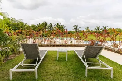 two lounge chairs and a table on the grass at Apartamento Acceso Directo a la piscina A-108, A-120, A-117 y B-137 in Punta Cana