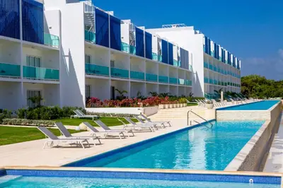 a hotel with a swimming pool and chairs and a building at Apartamento Acceso Directo a la piscina A-108, A-120, A-117 y B-137 in Punta Cana