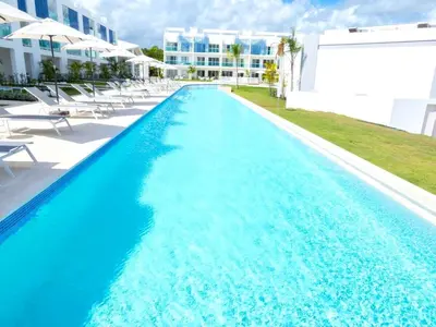 a swimming pool with blue water in front of a building at Apartamento Acceso Directo a la piscina A-108, A-120, A-117 y B-137 in Punta Cana