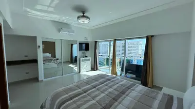 a white bedroom with a bed and a large window at Elegante Blue Marine Apartamento Juan Dolio in Juan Dolio