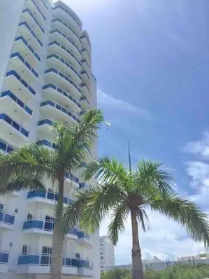 two palm trees in front of a large building at Elegante Blue Marine Apartamento Juan Dolio in Juan Dolio