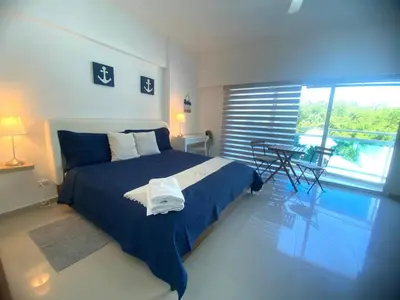 a bedroom with a bed and a table and a window at Elegante Blue Marine Apartamento Juan Dolio in Juan Dolio