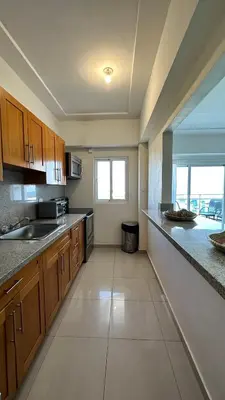 a large kitchen with wooden cabinets and a sink at Blue Boat Lindo Apartamento en Playa Juan Dolio in Juan Pedro