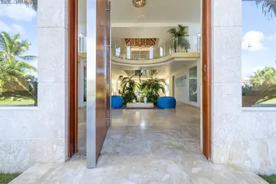 an open door to a house with palm trees at Luxury Rentals in Punta Cana - Exclusive Waterfall Villa with Private Pool, BBQ, Maid, Golf in Punta Cana