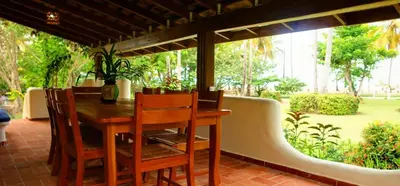 a table and chairs on a patio with a view of a garden at Villa directly on the beach, las Ballenas in Las Terrenas