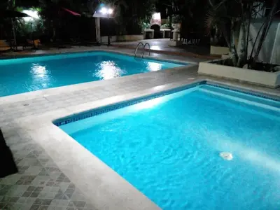 a large swimming pool with blue water at night at Villa Los Almendros - 2 private pools tennis pickle ball in Baní