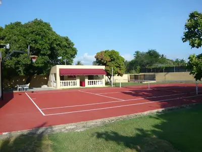 a tennis court in front of a building at Villa Los Almendros - 2 private pools tennis pickle ball in Baní