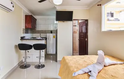 a room with a bed and two stools in a kitchen at Modern Tropical Studio with Terrace 300 Mbps Wi-Fi, Generator Gated Parking in La Viva